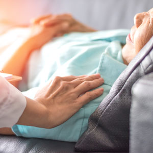 picture of hand comforting person laying in hospital bed