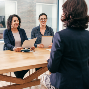Two women sitting across table interviewing third woman
