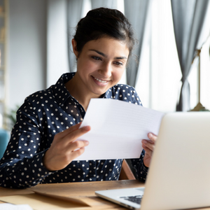 Picture of woman at desk looking at piece of paper and smiling