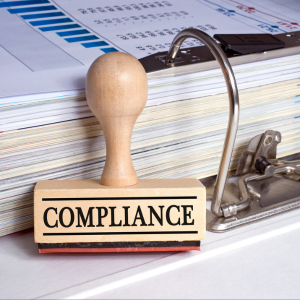 Compliance rubber stamp with binder and paper in the office