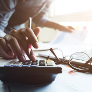 Picture of woman working on calculator with glasses and papers on desk