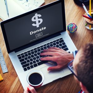 Picture of man looking at laptop screen that reads Donate, Go, click here for more information