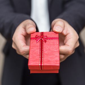 Picture of man's hands holding out a small red gift box