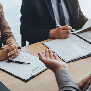 Two people sitting at table with resume interviewing third person on other side of table