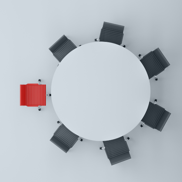 Round table with black chairs around it, one chair is red.