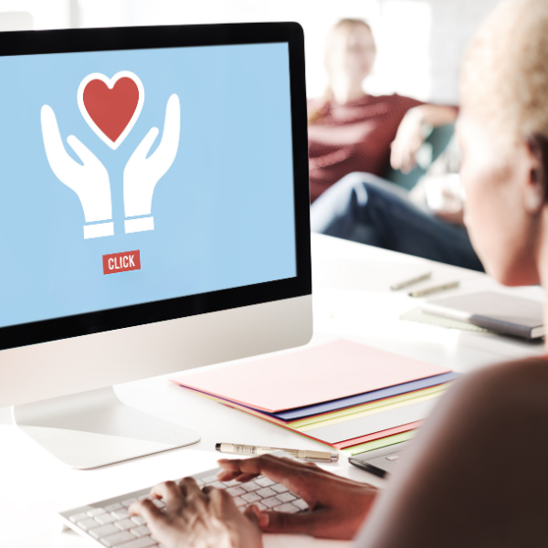 Person looking at computer screen that has image of two hands with a heart and a Click button