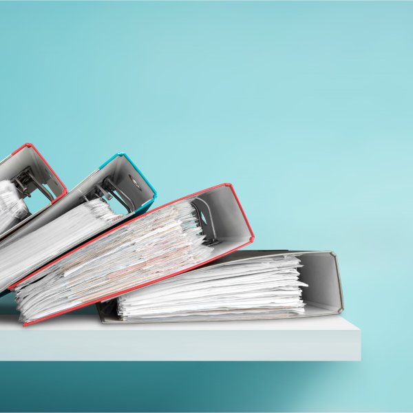 Four binders laying on white shelf with blue background