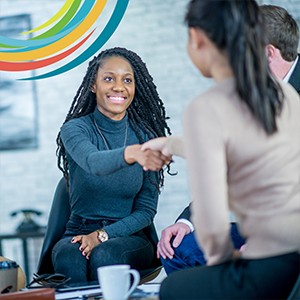 Smiling woman shaking hands with colleague. In the top left is an enlarged, but partial series of colourful arcs from CCCC logo
