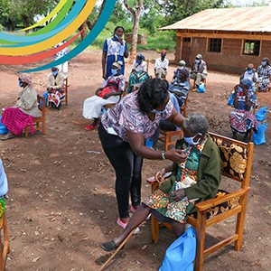 Group of elderly patients sitting outside of hospital in African village