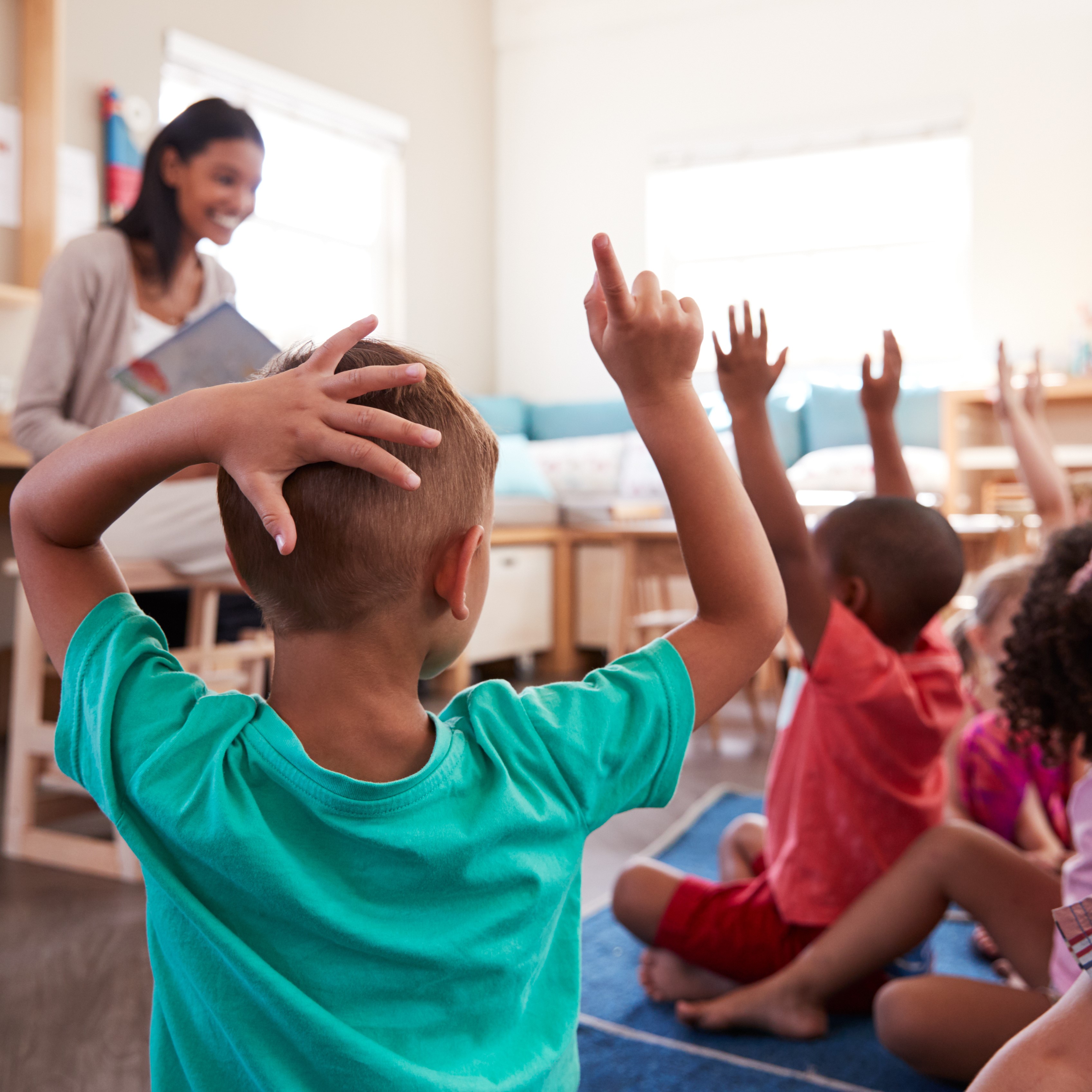 picture of female teacher sitting on chair teaching young children seated on ground