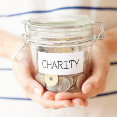 Picture of hands holding jar with label reading CHARITY and jar is filled with money