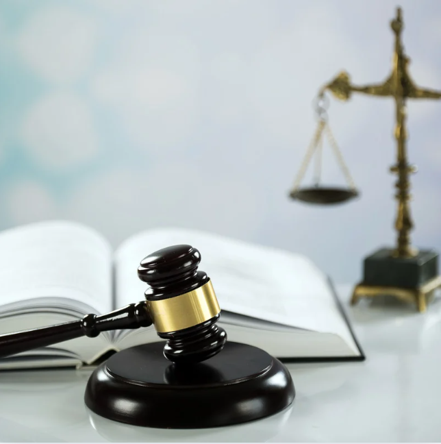 Judges gavel with book and scales of justice in background