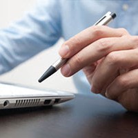picture of man's hand holding a pen with laptop