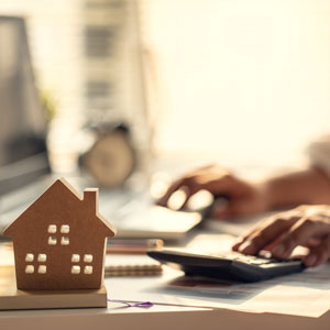 hand_on_calculator_with_image_of_house_in_foreground