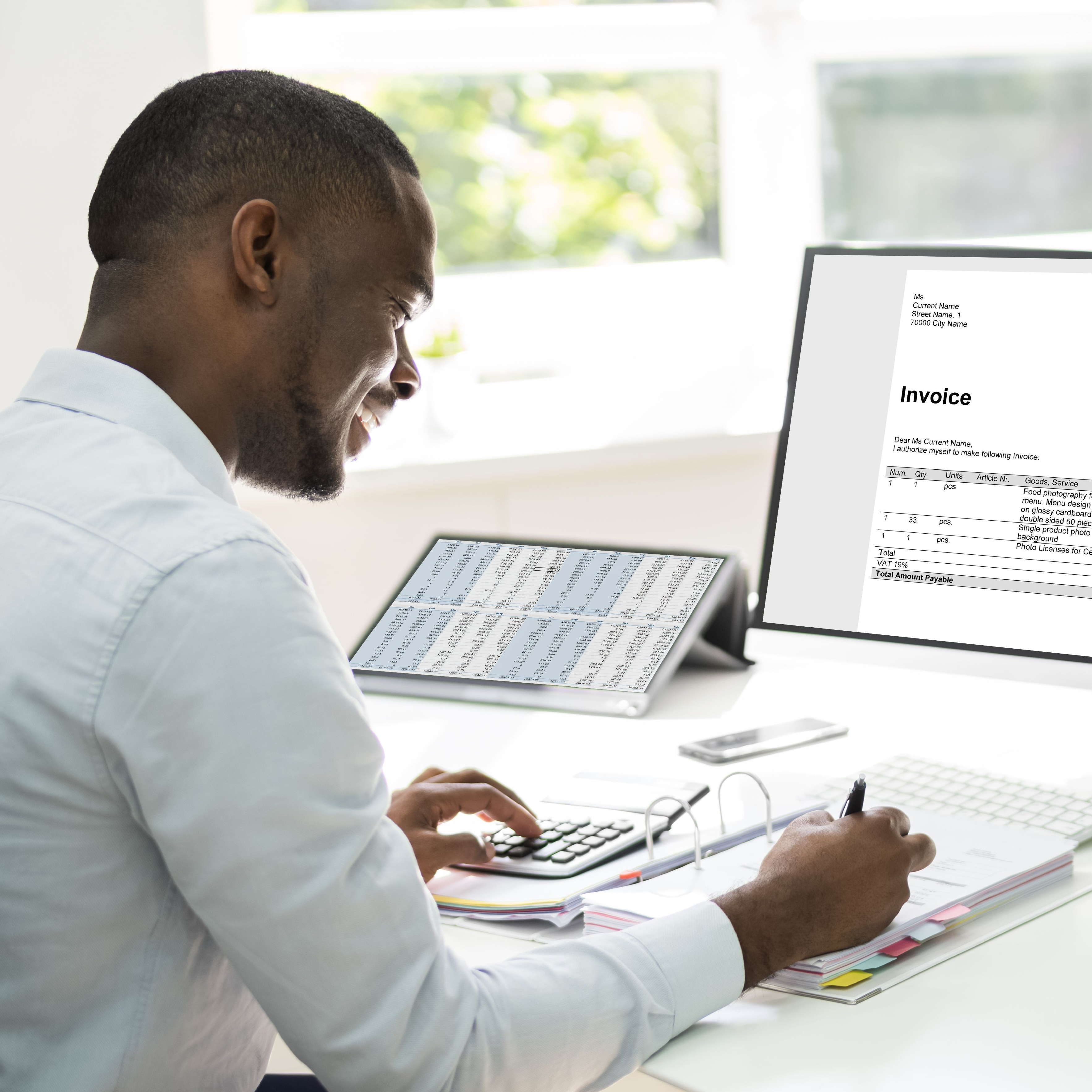 Picture of man at desk working with calculator and computer