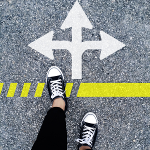 Picture of person's shoes walking on pavement with 3 arrows drawn on pavement. One points forward, one points left and one points right 