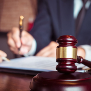 Picture of man signing document at desk with judge's gavel on desk