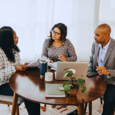 Three business colleagues sitting at table talking. Two women and one man