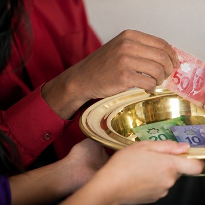 Two hands passing offering plate and putting money into plate