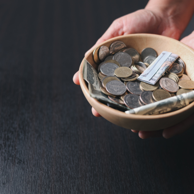 Hands holding bowl filled with offering money