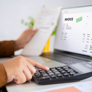 hand_on_calculator_with_computer screen showing an invoice
