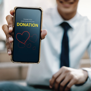 Man with cell phone in hand and screen reads thank you for your online donation