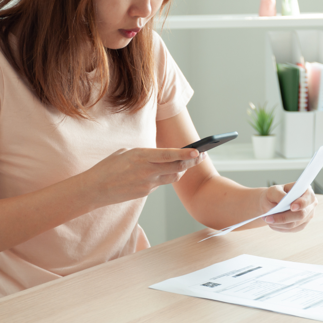 Woman with cell phone in hand holding receipt in another hand