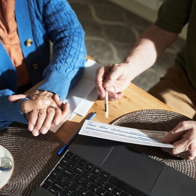 Two people sitting at table but only hands are showing.  One hand is holding a cheque
