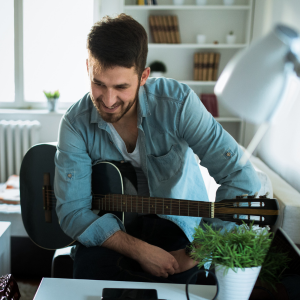 Picture of man with guitar looking at electronic device