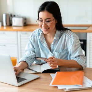 Picture of smiling woman looking at laptop holding credit card