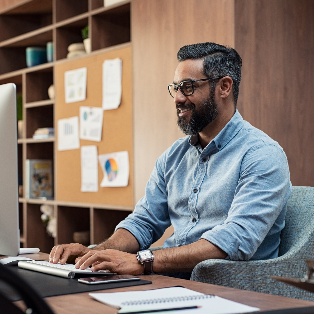 Smiling man sitting at desk with keyboard and computer screen