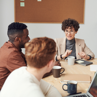 Three colleagues around meeting table talking 
