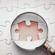 Picture of puzzle with missing puzzle piece and magnifying glass laying on top of puzzle
