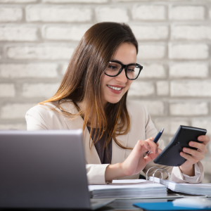 Smiling woman working at desk looking at calculator
