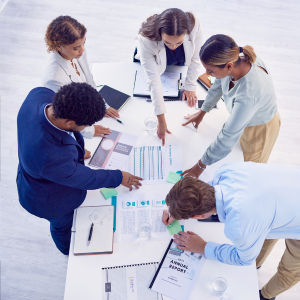 Picture of five colleagues standing around a table looking at financial docs