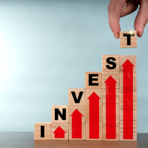 Picture of wooden blocks letters spelling the word invest and each letter increases in height with red arrow pointing up beneath it.