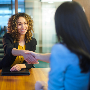 Picture of smiling woman shaking hands with another woman across a table