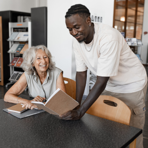 Picture of two work colleagues looking at book and smiling