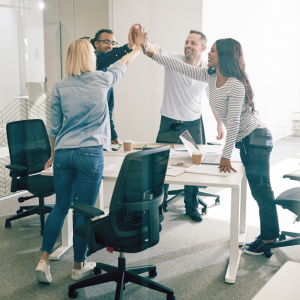 Group of smiling colleagues standing around meeting table with hands outstretched and touching in a team building gesture