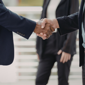 Picture of two men shaking hands. Only the arms and hands are pictured.