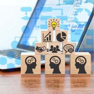 Picture of wooden blocks with images on them, stacked in front of laptop indicating sharing knowledge by technology