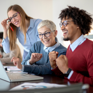 Picture of three work colleagues looking at laptop smiling, two women, one man