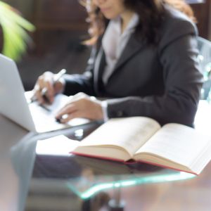Professional woman working at desk with laptop and open book on desk