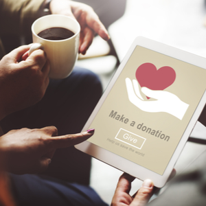 Picture of two people looking at laptop screen reading Make a donation with the image of a hand holding a heart