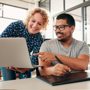 Picture of smiling colleagues - one male and one female - looking at a laptop