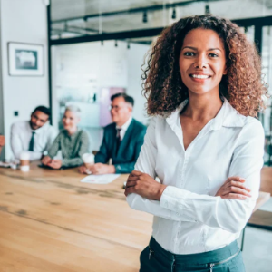 Picture of female leader with colleagues in background sitting at meeting table