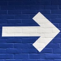 picture of large white arrow pointing to the right on a blue painted brick background