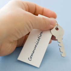 Picture of hand holding key, key holder and key label with the word Communication on label