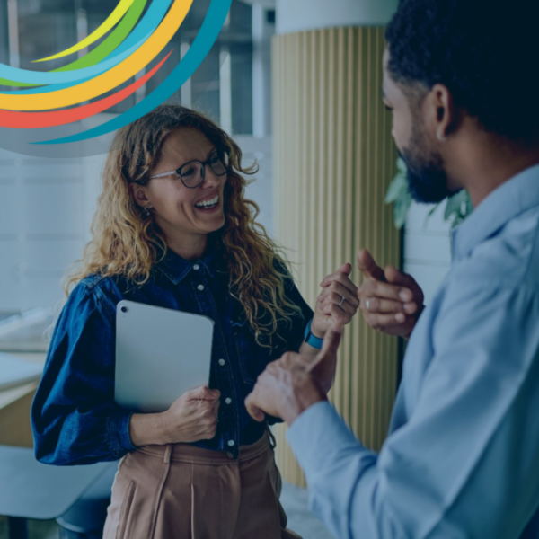 Two work colleagues, man and woman, standing and smiling and talking
