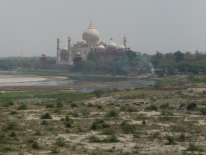 A cremation at the river's edge with Taj Mahal in background